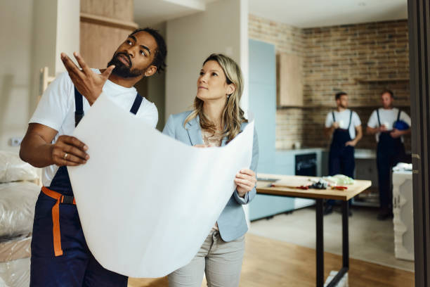istock Female architect and black worker making plans in moving apartment. 1489394925