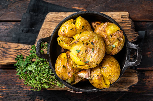 triturado, patatas rotas horneadas en aceite con hierbas. fondo de madera. vista superior - smashed potatoes fotografías e imágenes de stock