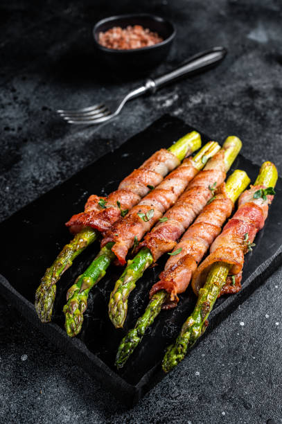 istock Asparagus Baked with bacon and spices. Black background. Top view 1489397346