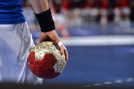 Handball Player with sportstape on his fingers, warming up while holding a handball