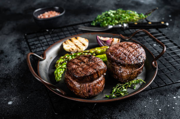 Grilled Fillet Mignon Steak with roasted asparagus. Black background. Top view