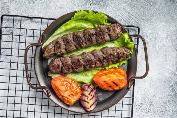 Grilled Urfa kebab with tomato, salad and onion. Black background. Top view.