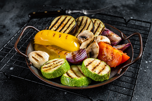 Grilled vegetables, bell pepper, zucchini, eggplant, onion and tomato. Black background. Top view.