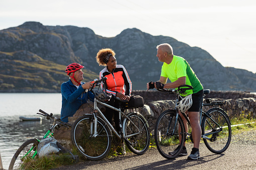 Friends at the bay near the village of Diabaig on the side of Loch Torridon in Wester Ross, Scotland. They are taking a break from their bike ride to relax and chat. They are laughing together.