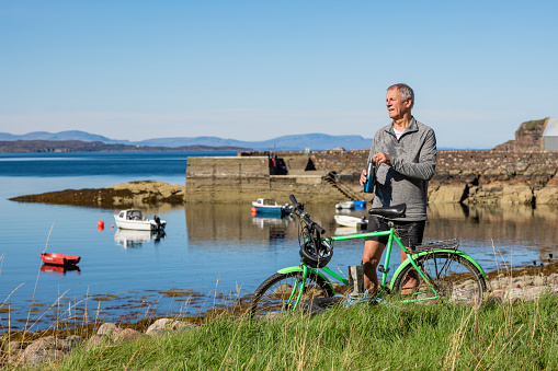 Senior man on a bike ride at the bay near the village of Diabaig on the side of Loch Torridon in Wester Ross, Scotland.