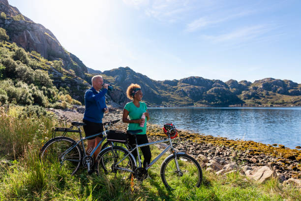 Friends at the bay near the village of Diabaig on the side of Loch Torridon in Wester Ross, Scotland. They are taking a break from their bike ride to relax and chat. They are looking out at the view together.