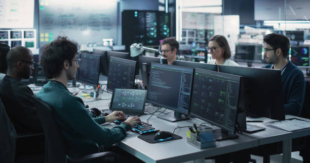 istock Group of Empowered Multicultural Men and Women Working in a Research Center, Using Computers to Run Advanced Software, Develop Artificial Intelligence Interface and Cyber Security Protocols 1489403570