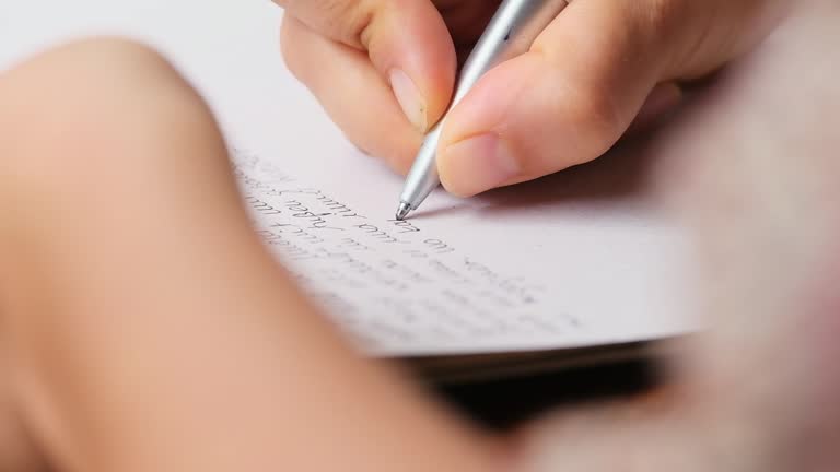 closeup of a hand journaling on a table in front of blurry green jungle