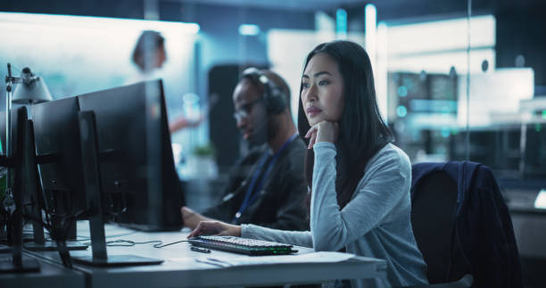 Portrait of a Thoughtful Asian Engineer Working on Computer in a Technological Corporate Laboratory. Young Woman Writing Software Code for an Innovative Internet and Software as a Service Project