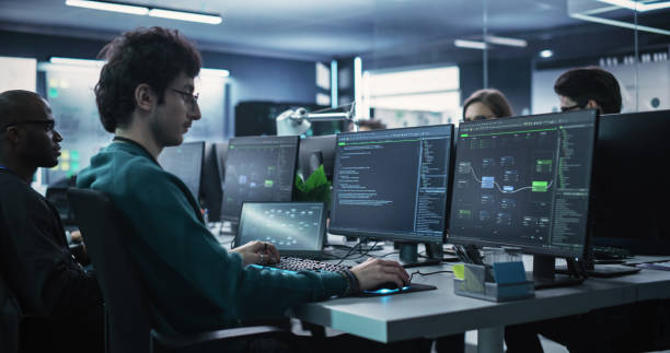istock Team of Talented Young Professionals Working in a Technological Research and Development Agency. Computer Screens with Software Code, Customer Relationship Management Tool and Road Map User Interface 1489404392
