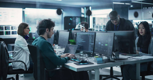 istock Team of Talented Young Professionals Working in a Technological Research and Development Facility. Diverse Specialists Using Computers, Writing Code, Planning Innovative Information Technology Project 1489404421