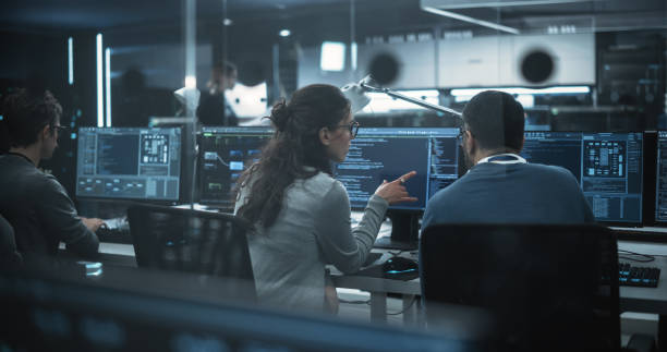 istock Diverse Young Colleagues Working on Computers in a Research Laboratory. Female Asking Advice from a Male Software Developer Colleague About a Solution for Their Collaborative Industrial Tech Project 1489412181