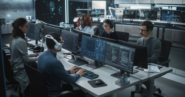 istock Team of Talented Young Professionals Working in a Technological Research and Development Agency. Computer Screens with Software Code, Customer Relationship Management Tool and Road Map User Interface 1489414671