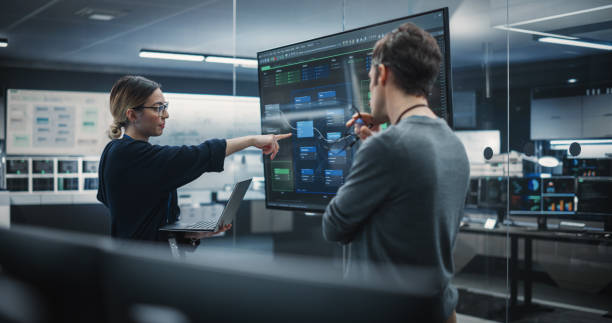 dois desenvolvedores de software diversos tendo uma reunião em uma sala de conferência. mulheres e homens engenheiros da indústria de tecnologia debatendo ideias para sua startup blockchain de rede neural - mobiles internet - fotografias e filmes do acervo