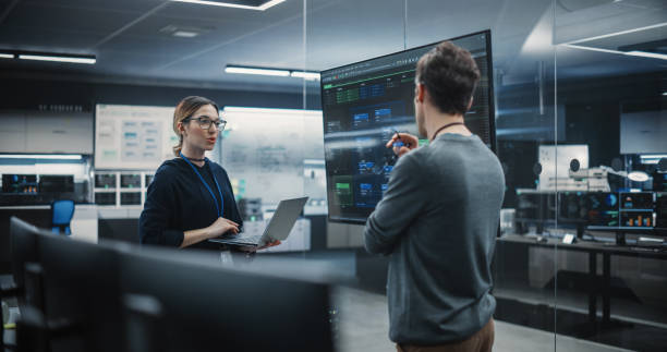 istock Two Diverse Software Developers Having a Meeting in a Conference Room. Female and Male Tech Industry Engineers Brainstorming Ideas for Their Neural Network Blockchain Startup 1489415062