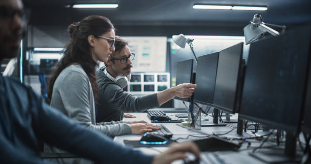 istock Young Colleagues Working on Computers and Talking at a Workplace. Female and Male Software Developers Discussing a Solution for Their Collaborative Artificial Intelligence Project 1489415076
