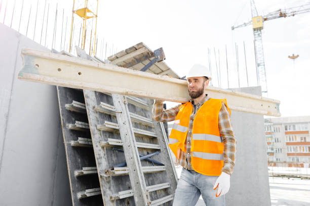istock Builder man in hardhat and vest carrying timber on building site in his working day 1489416903