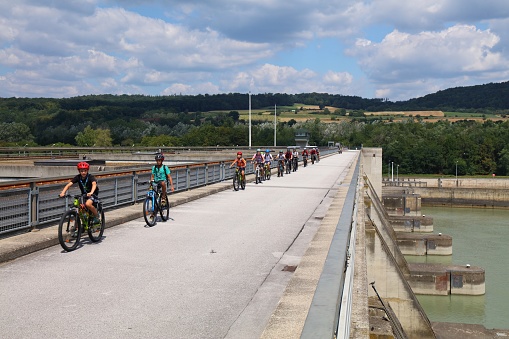 Cyclists ride famous Danube Cycle Route (Donauradweg) on Danube River dam in Wachau region of Austria.