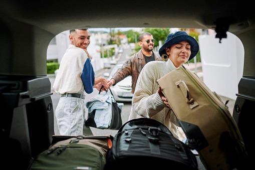POV of LGBTQIA friends packing a car with luggage before departing on a road trip