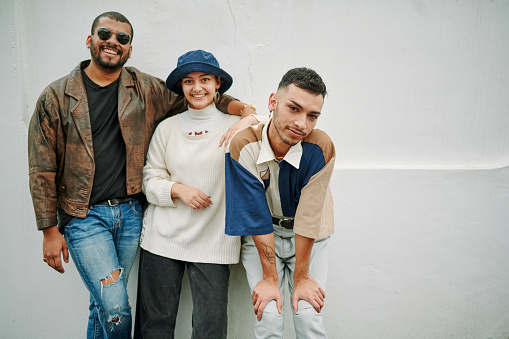 Portrait of young fashionable LGBTQIA friends side by side looking at the camera with a white background