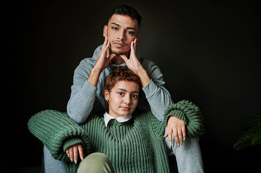 Closeup portrait of LGBTQIA friends leaning onto each other with a cool attitude on a black background. LGBTQIA Lifestyle