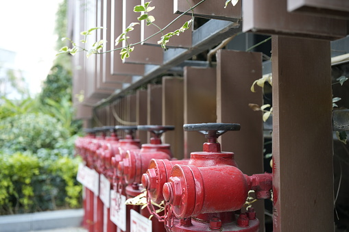 A vibrant red fire hydrant stands prominently against a neutral urban background. The silver top contrasts with the bright red body, emphasizing its functionality and importance.