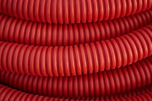 Corrugated for insulation cable of wires underground, plastic tube, electricity protection pipe for construction works, red corrugation close-up with copy space. High quality photo