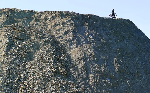 Difficult bike tour on the edge of the abyss of a huge waste mountain