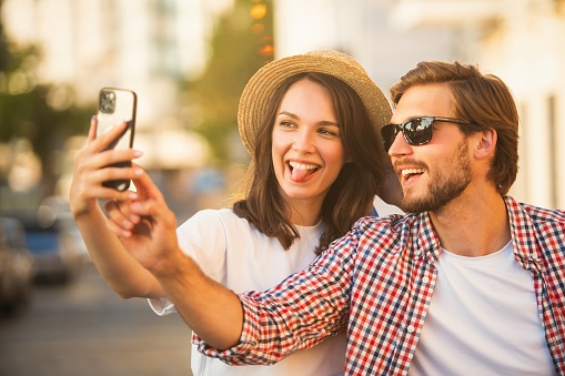 Loving cheerful happy couple taking selfie in the city
