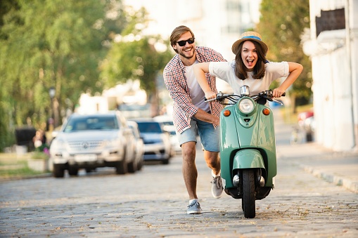 Laughing couple riding on a scooter in town