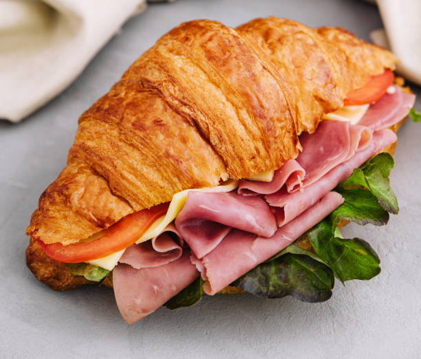 istock French croissant sandwich with lettuce , cheese , tomatoes and ham 1489431282