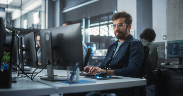 istock Portrait of a Thoughtful Engineer Working on Desktop Computer in a Technological Office Environment. Research and Development Department Writing Software Code for an Advanced Neural Network Project 1489431840