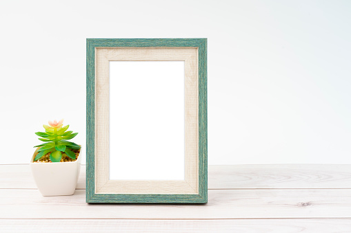 Blank picture frame and plant pot on wooden floor with copy space and clipping path for the inside.
