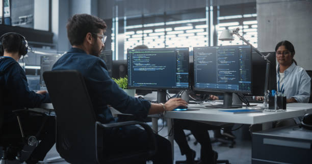 istock Team of Talented Young Indian Professionals Working in a Technological Research and Development Agency. Computer Screens with Software Code and Technical Neural Network Diagrams 1489432464
