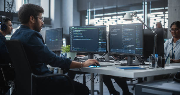 istock Team of Talented Young Indian Professionals Working in a Technological Research and Development Agency. Computer Screens with Software Code and Technical Neural Network Diagrams 1489432500