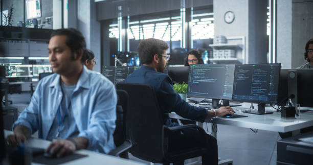 istock Team of Talented Young Indian Professionals Working in a Technological Research and Development Agency. Computer Screens with Software Code and Technical Neural Network Diagrams 1489432546
