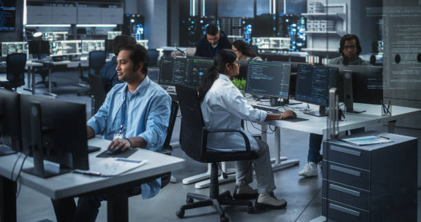 istock Team of Talented Young Indian Professionals Working in a Technological Research and Development Agency. Computer Screens with Software Code and Technical Neural Network Diagrams 1489432598