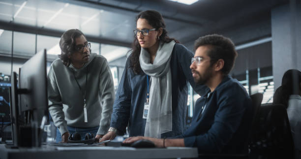 istock Team of Three Multiethnic Diverse Software Developers Talk, Discuss an AI Project. Stylish Young Indian Female and Male Specialists Work on Digital E-Commerce Startup Business 1489432772