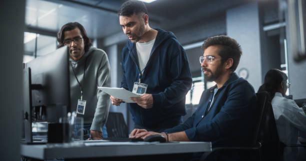 istock Team of Three Multiethnic Diverse Software Developers Talk, Discuss and Collaborate on an AI Project. Empowered Young Indian Specialists Work on Digital E-Commerce Startup Business 1489433321