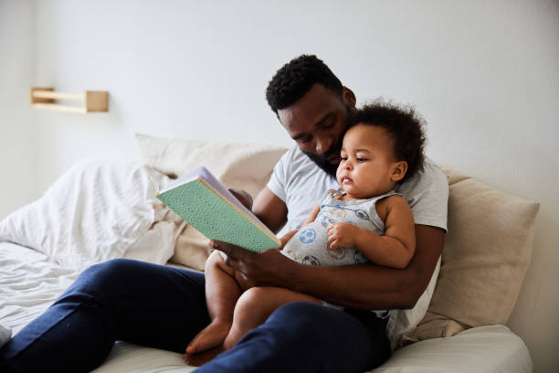istock Smiling dad reading a his little son a book in bed 1489434374