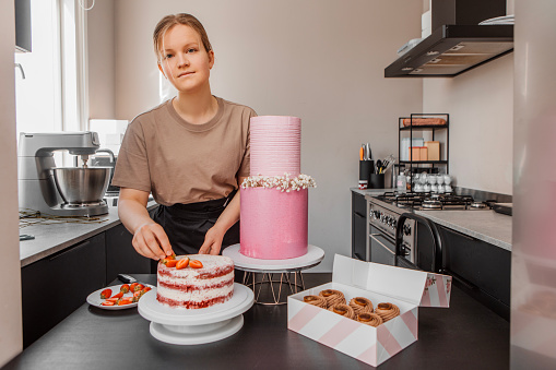 Beautiful professional female baker preparing a cake for delivery