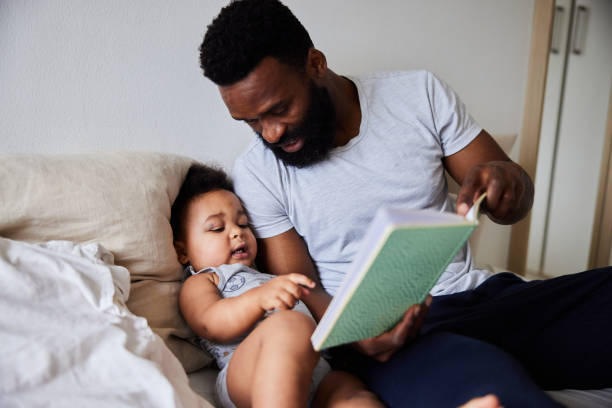 istock Smiling dad reading a his little boy a book in bed 1489437464