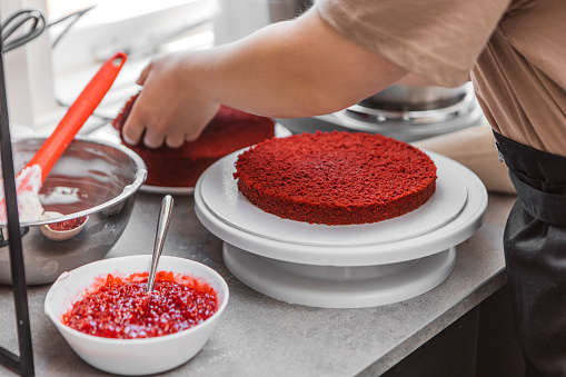 Close up of female hands working on red velvet cake baking in a home kitchen