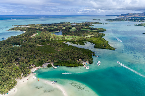 Beautiful island beach with palm trees and blue sky leading out to the open ocean. Ile Aux Cerfs, Mauritius. Aerial view of sandy beach and golf course. Aerial drone view of the beautiful tropical ocean beach from above. Summer sunshine seascapes.