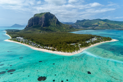 Aerial top down view of Le Morne Brabant Mountain, Mauritius. Beautiful vibrant beach and clear blue water. Ocean waves on the beach as a background. Beautiful natural summer vacation holidays background. Coastal seascapes, Underwater Waterfall