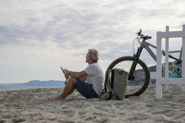 Male bicyclist relaxes on empty beach