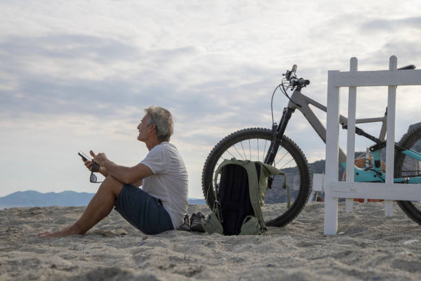istock Male bicyclist relaxes on empty beach 1489440895