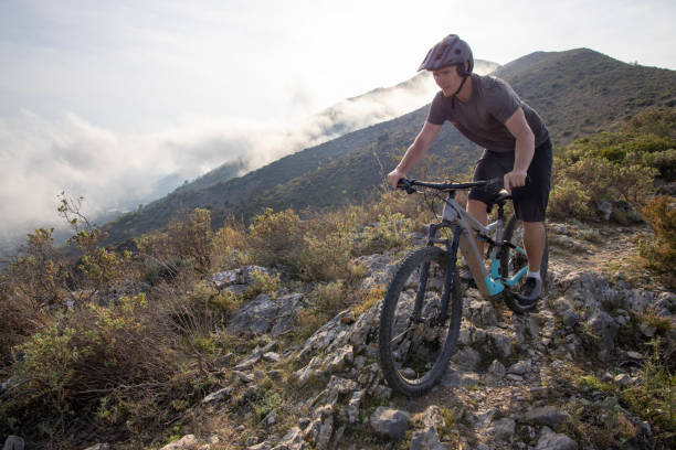 istock Male mountain biker descends rocky path through hills 1489441346