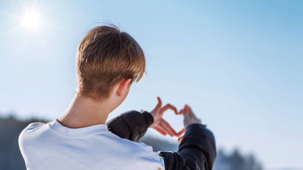 Love everything . Teenager Hands forming a heart shape Teenager folded Two hands on the background of the sky with join fingers in the shape of a heart, show a gesture of love, show their feelings cute boy show love symbol hand stock pictures, royalty-free photos & images