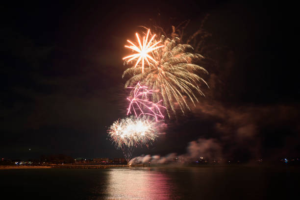 istock Aerial view of bright fireworks exploding with colorful lights over sea shore on US Independence day holiday 1489452705
